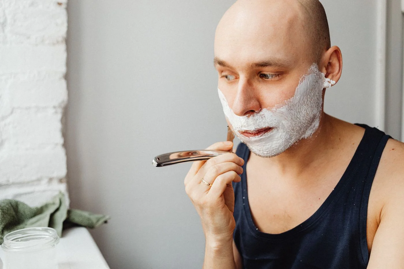 Man shaving his face with shaving cream and a straight razor